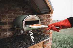 a person is putting a pizza into an oven at Ewe and Me Glamping in Northallerton