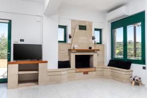 a living room with a fireplace and a flat screen tv at Villa Giannari in Stalos