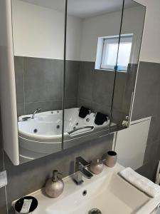 a bathroom with a tub and a sink with a mirror at Freiblick 3 Bad Glbg mit Terrasse Top 3 in Bad Gleichenberg