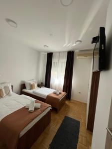 een hotelkamer met 2 bedden en een flatscreen-tv bij For5 in Ðakovo