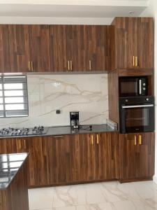 a kitchen with wooden cabinets and a stove and microwave at Luxe Dandji in Cotonou