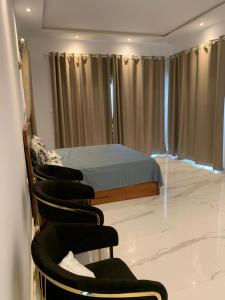 a bedroom with a bed and chairs in a room at Luxe Dandji in Cotonou