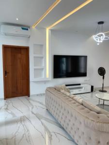 sala de estar con sofá grande y TV de pantalla plana en Luxe Dandji, en Cotonou