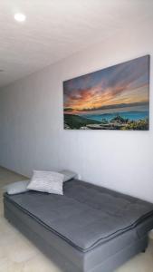 a bed in a room with a painting on the wall at New Modern Condo with Air-condition in Zapotlanejo