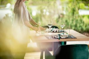 een vrouw aan een tafel met wijnglazen bij Taubers Bio Vitalhotel in Chienes