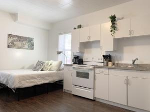 una cocina con armarios blancos y una cama en una habitación en Cozy Bachelor Condo l Downtown l WiFi & Smart TV, en Moose Jaw