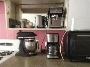 a kitchen counter with a coffee maker and a microwave at Habitaciones con baño compartido en Departamento Mid Century Modern in Mendoza