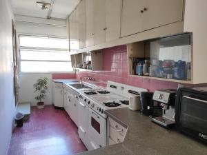 a kitchen with white appliances and pink walls at Habitaciones con baño compartido en Departamento Mid Century Modern in Mendoza