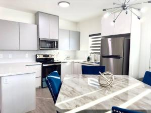 a kitchen with white cabinets and a table with blue chairs at Brand New Apt! Close to the Mall in McAllen