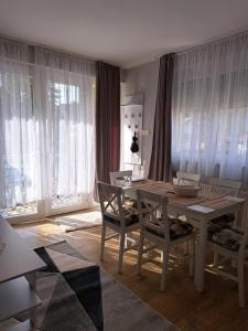 a dining room with a table and chairs and windows at Jázmin Apartman Zalakaros in Zalakaros