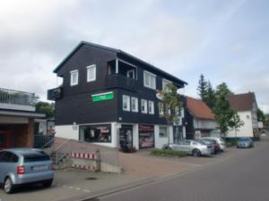 un edificio negro con coches aparcados delante en Bergwelt Braunlage, en Braunlage