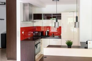 uma cozinha com armários brancos e paredes vermelhas em Kraków Główny Apartment - Parking, Workspace - by Rentujemy na Cracóvia