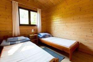 two beds in a log cabin with a window at Ośrodek Wypoczynkowy NA WYDMIE in Dziwnów
