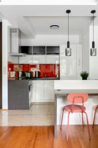 a kitchen with red and white cabinets and a pink chair at Kraków Główny Apartment - Parking, Workspace - by Rentujemy in Krakow