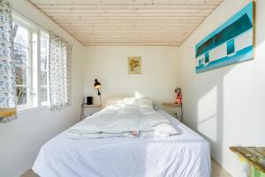 Schlafzimmer mit einem Bett mit weißer Bettwäsche und einem Fenster in der Unterkunft Idyll Summer house in Hornbæk in Hornbæk