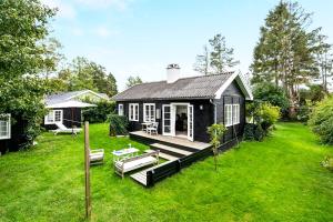 uma casa preta com um deque e um quintal em Idyll Summer house in Hornbæk em Hornbæk