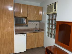 a small kitchen with wooden cabinets and a microwave at Grand Hotel Betsy in Lima