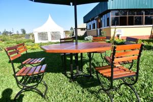 einem Picknicktisch mit zwei Stühlen und einem Sonnenschirm in der Unterkunft Koma Gardens and Resort in Nguluni