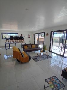 a living room with couches and tables and windows at Villa avec piscine in Saint-Gilles