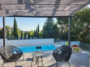 un patio con 2 sillas, una mesa y una piscina en Villa avec piscine, en Saint-Gilles