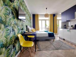 a bedroom with a bed and a table and yellow chairs at Olivia Apartments - Słoneczny apartament w centrum Warszawy, Plac Unii Lubelskiej, Łazienki Królewskie, Pole Mokotowskie - 24h check-in in Warsaw