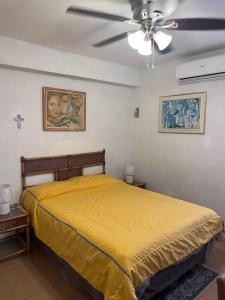 a bedroom with a yellow bed and a ceiling fan at TRANQUILO Y ESPACIOSO DEPARTAMENTO AMBASSADOR in Campo de Carabobo