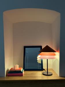 uma lâmpada sobre uma mesa com livros e um espelho em Hilaris em Putignano