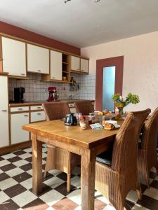 eine Küche mit einem Holztisch und Korbstühlen in der Unterkunft Maison bord de Marais proche Plage du Débarquement in Auvers