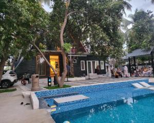 una piscina al lado de una casa con gente sentada alrededor en Moon Light Resorts, en Ammāpettai