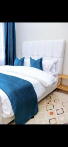 a large bed with blue and white pillows in a room at Indesign makumbi park Elegant 2 bedrooms in Nairobi