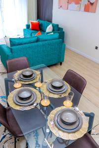 a table with plates and glasses on it in a living room at Indesign makumbi park Elegant 2 bedrooms in Nairobi