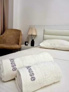 um quarto com 2 camas com lençóis brancos e uma cadeira em New House Kobuleti em Kobuleti