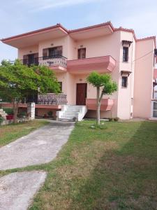 uma casa cor-de-rosa com uma árvore em frente em House in the Village em Ráxa