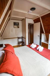 ein Schlafzimmer mit einem großen Bett mit roter Bettwäsche und einem Stuhl in der Unterkunft Apart Hotel Ensueño in San Martín de los Andes