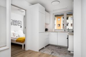 biały apartament z łóżkiem i kuchnią w obiekcie Szczawnica Art w mieście Szczawnica