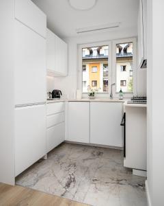 uma cozinha branca com armários brancos e uma janela em Szczawnica Art em Szczawnica