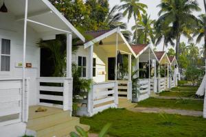 een rij witte huizen met palmbomen op de achtergrond bij Seawood beach front resort in Morjim