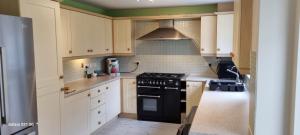 a kitchen with white cabinets and a stove top oven at Eden Escape in Ashford