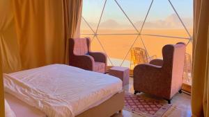 een kamer met een bed, 2 stoelen en een raam bij Wadi Rum Joy camp in Disah
