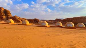 een rij koepels in de woestijn met rotsen bij Wadi Rum Joy camp in Disah