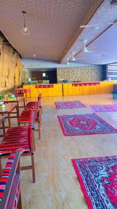 een kamer met tafels, stoelen en matten op de vloer bij Wadi Rum Joy camp in Disah