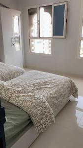 a bed in a white room with two windows at عنوان التميز غرفتين نوم بدخول ذاتي in Dammam