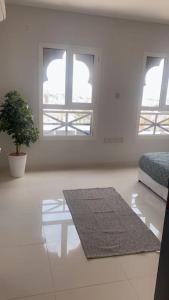 a living room with two windows and a rug at عنوان التميز غرفتين نوم بدخول ذاتي in Dammam