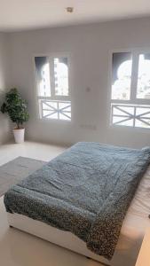 a bedroom with two windows and a bed with a blanket at عنوان التميز غرفتين نوم بدخول ذاتي in Dammam