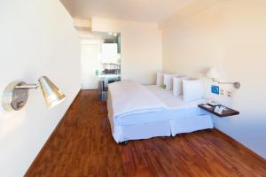 1 dormitorio con cama blanca y suelo de madera en Hotel LP Columbus, en La Paz