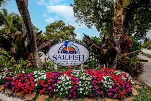 a sign for a resort with flowers in a garden at Dog friendly condo with beach access, hot tub, firepit in West Palm Beach
