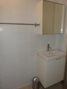 La salle de bains blanche est pourvue d'un lavabo et d'un miroir. dans l'établissement APPARTEMENT COEUR DE LA STATION, à Mimizan