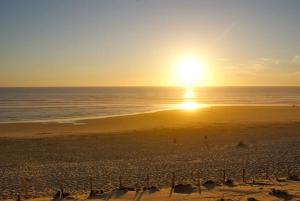 - une plage au soleil se levant au-dessus de l'océan dans l'établissement APPARTEMENT COEUR DE LA STATION, à Mimizan