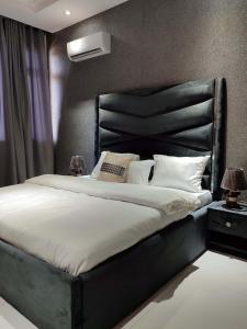 Un dormitorio con una cama grande con cabecero negro. en MISIN GREEN Grandeur Two Bedroom Apartment, en Lagos