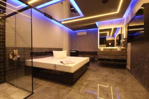 リメイラにあるMotel Deslize Limeira 1のベッドのある寝室と青い照明のあるバスルーム